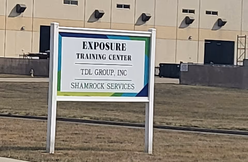 Outdoor signboard in front of a beige building displaying TDL Group, Inc. and Shamrock Services