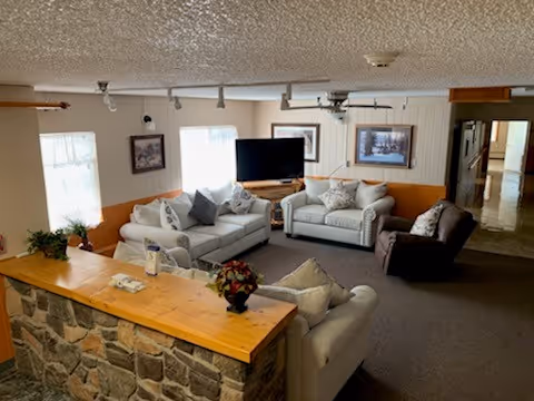 Cozy senior living lounge with multiple sofas, a stone counter, and a TV.
