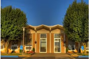 Front view of a brick senior living facility entrance with trees and glass doors.
