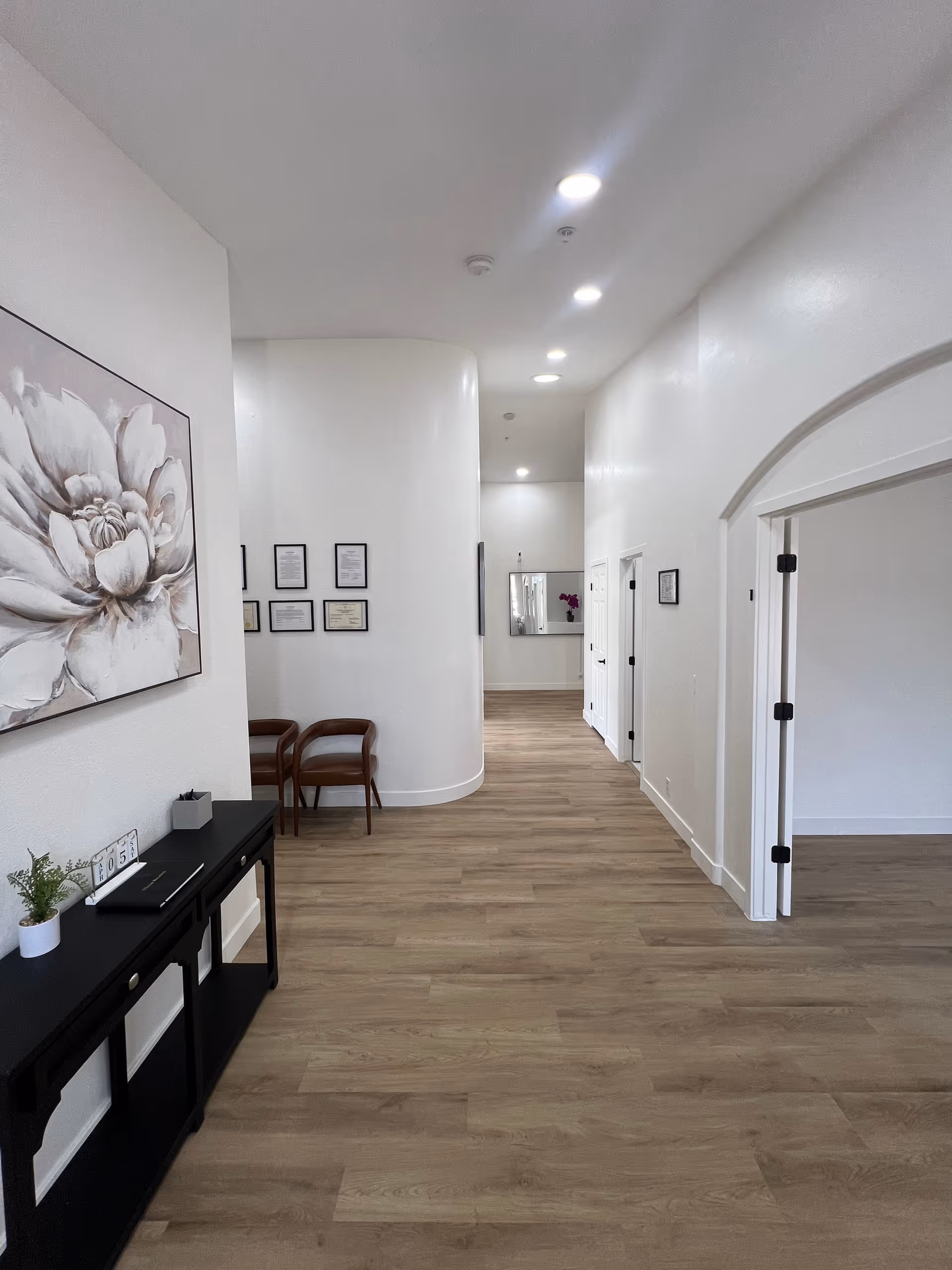 White hallway with wood flooring, seating, and large floral artwork in Horizon Manor I.