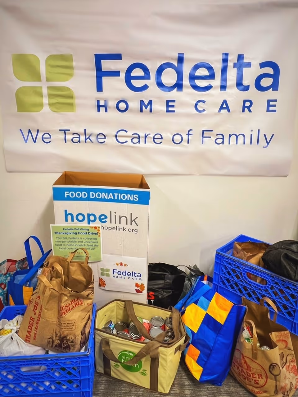 Interior scene with Fedelta Home Care banner and donation boxes surrounded by bags.
