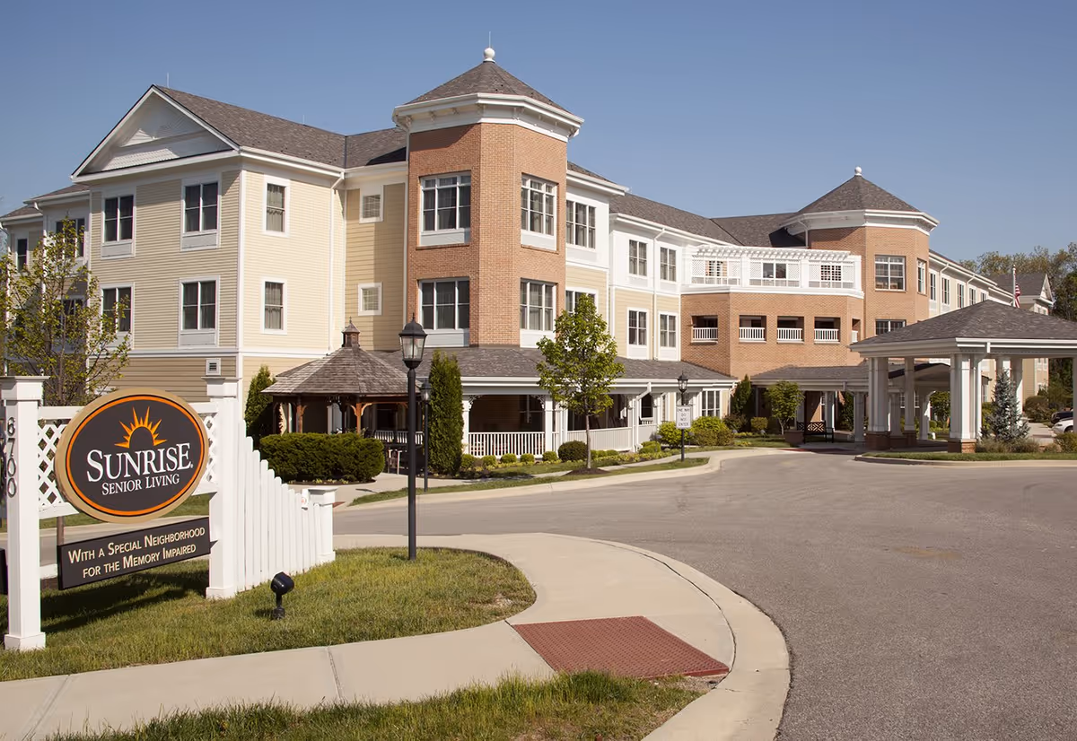 Exterior view of Sunrise Senior Living facility with a circular driveway and sign.