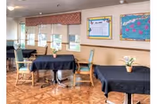A dining area with dark tablecloths, green chairs, and bulletin boards on the wall.