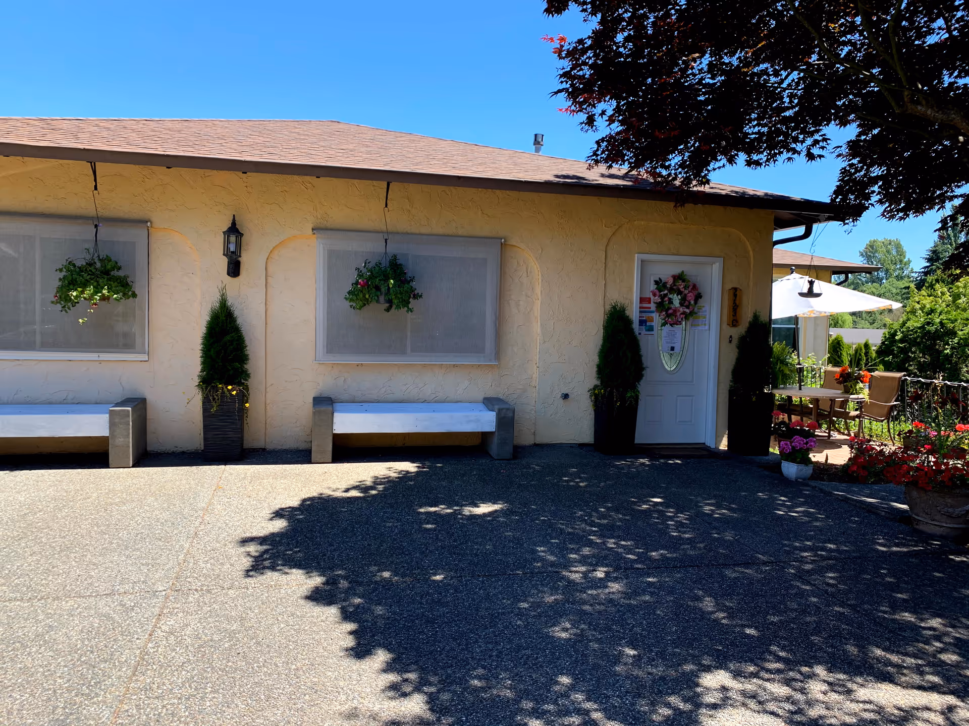 Exterior view of a beige building with hanging planters and outdoor seating.