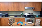 Wooden kitchen with cabinets, stove, and a dining table with chairs.