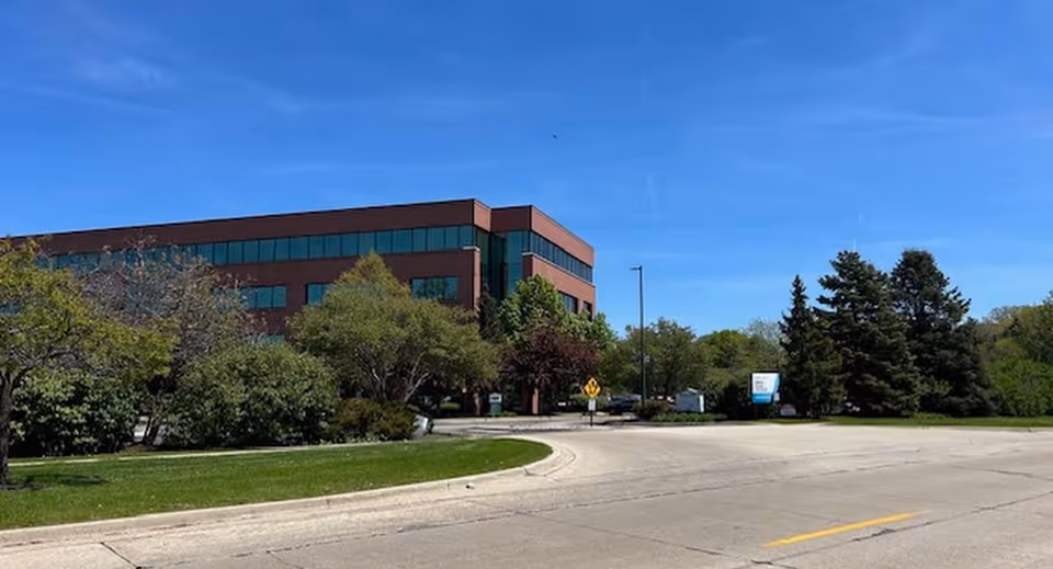 Exterior view of a brick, multi-story building with trees and a curved road.
