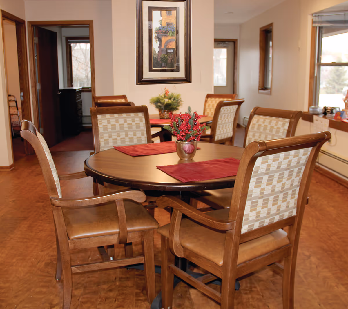 Round wooden dining table with chairs in a senior living dining room.