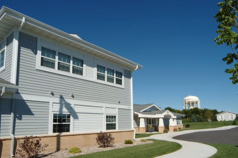 Exterior view of Autumn Grace senior living facility with walkway and lawn.