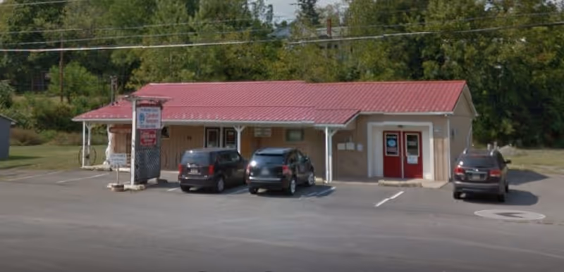 Front view of Comfort Keepers of Bloomsburg building with a red metal roof and parked cars.