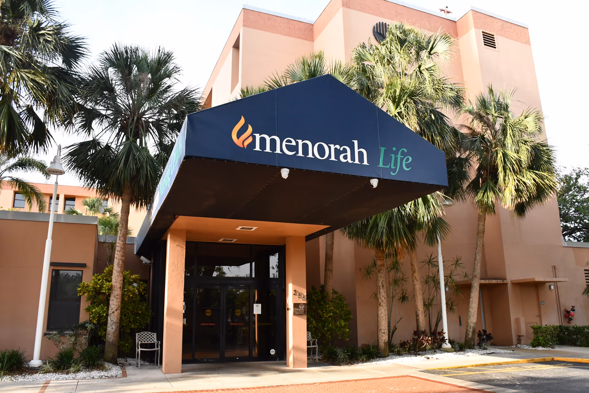 Exterior entrance of a nursing center with a blue canopy labeled menorah Life.