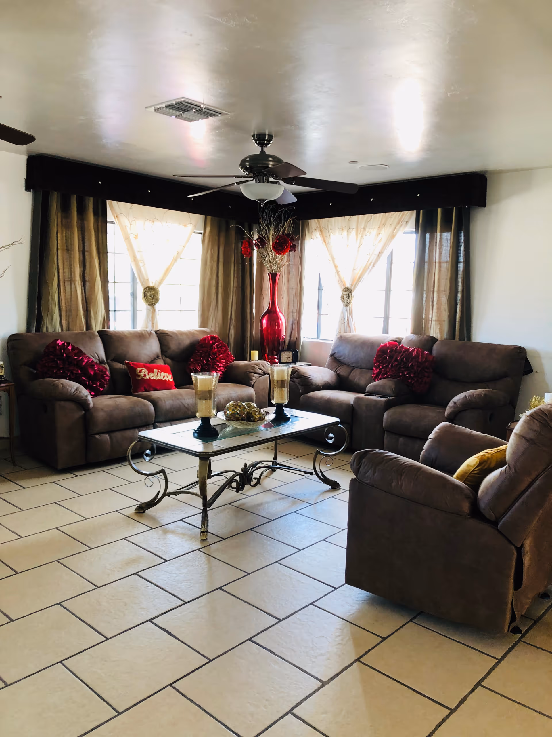 Cozy living room lounge with brown sofas, glass coffee table, and red decor.