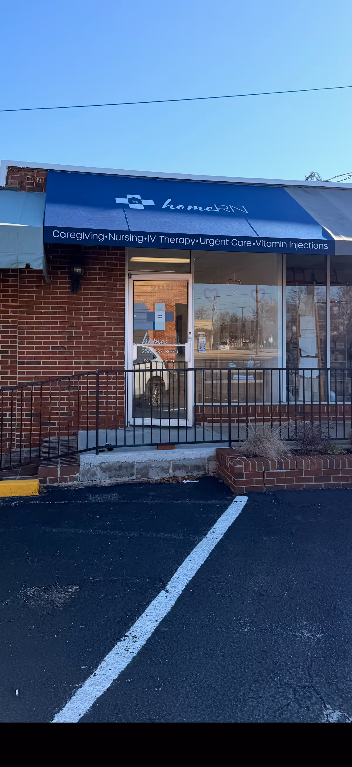 Exterior view of a brick building with a blue awning reading homeRN Huntsville.