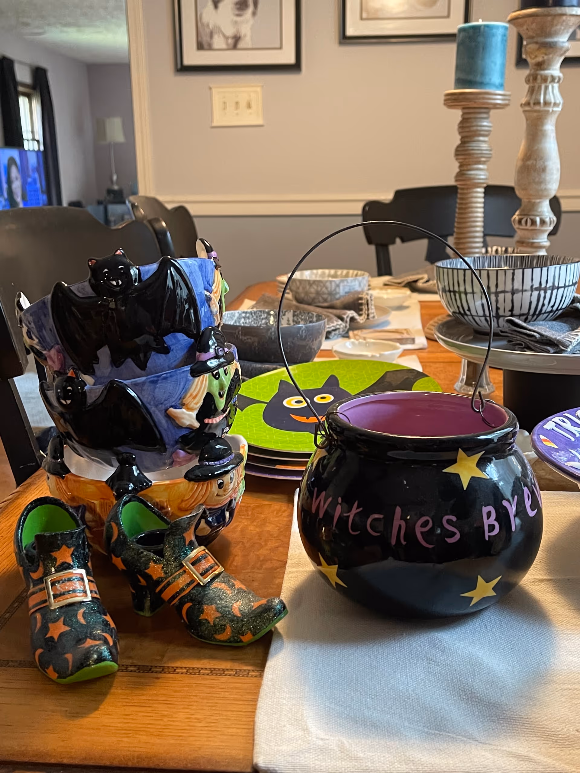 Halloween-themed dining table with a witch's cauldron, boots, plates, and candles.