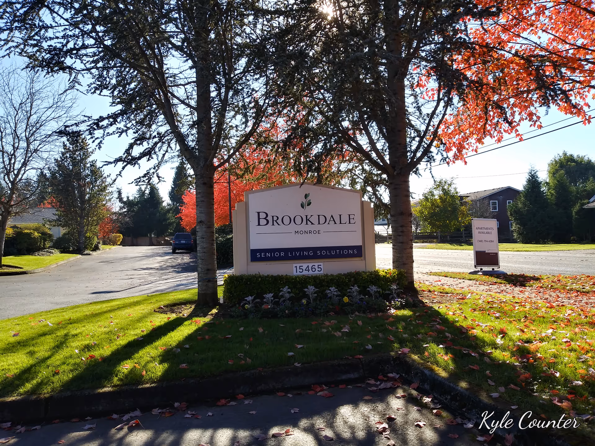 Brookdale Monroe exterior sign with landscaping and autumn trees at entrance
