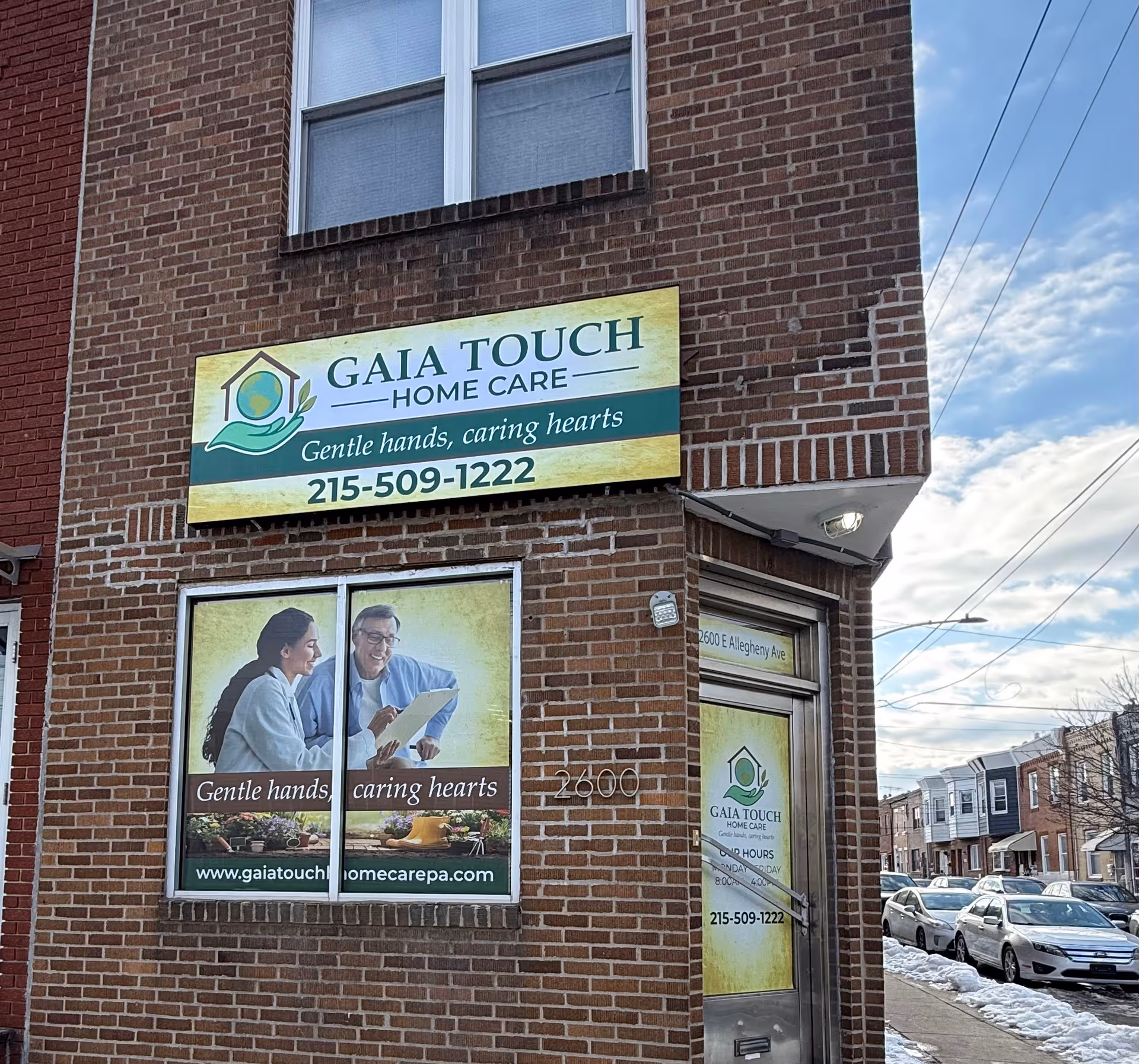 Brick building storefront with Gaia Touch Home Care sign and posters in the windows.