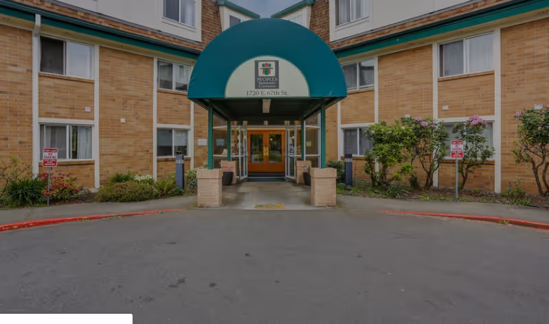 Front entrance of Peoples Senior Living with a green awning over the doors and a circular driveway.