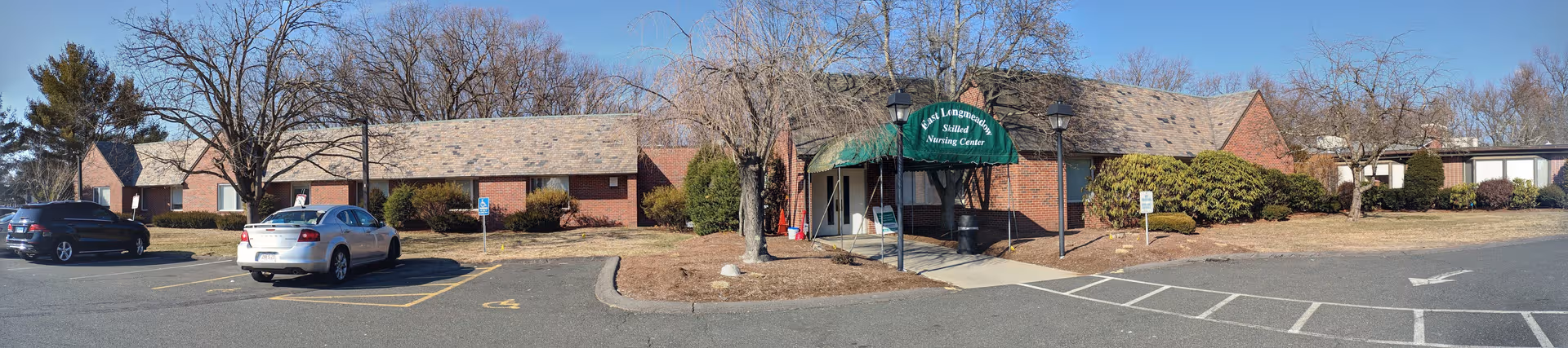 Exterior view of East Longmeadow Skilled Nursing Center with brick facade and parked cars.