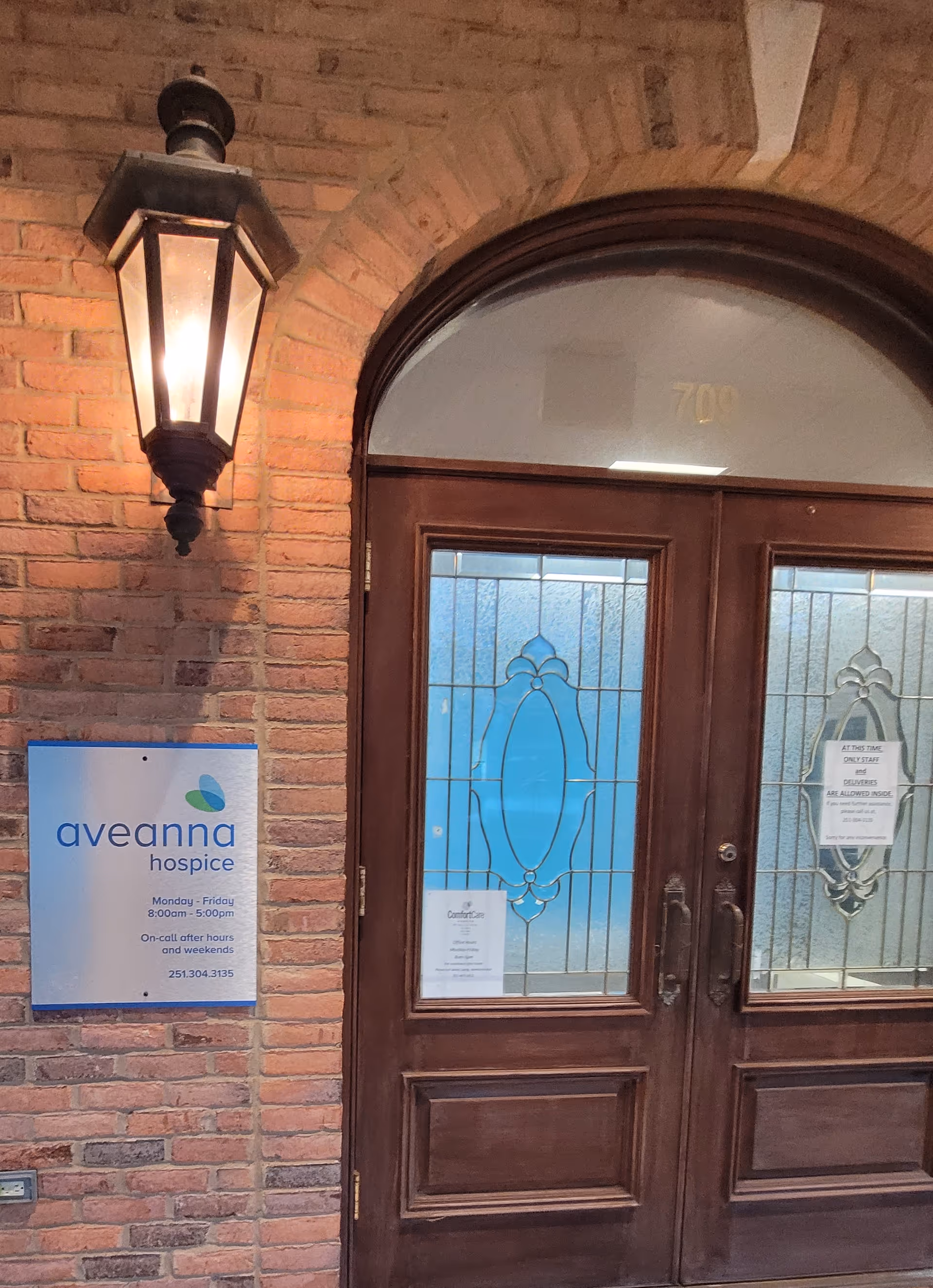 Brick exterior entrance with wooden double doors, decorative glass, and an illuminated lantern.