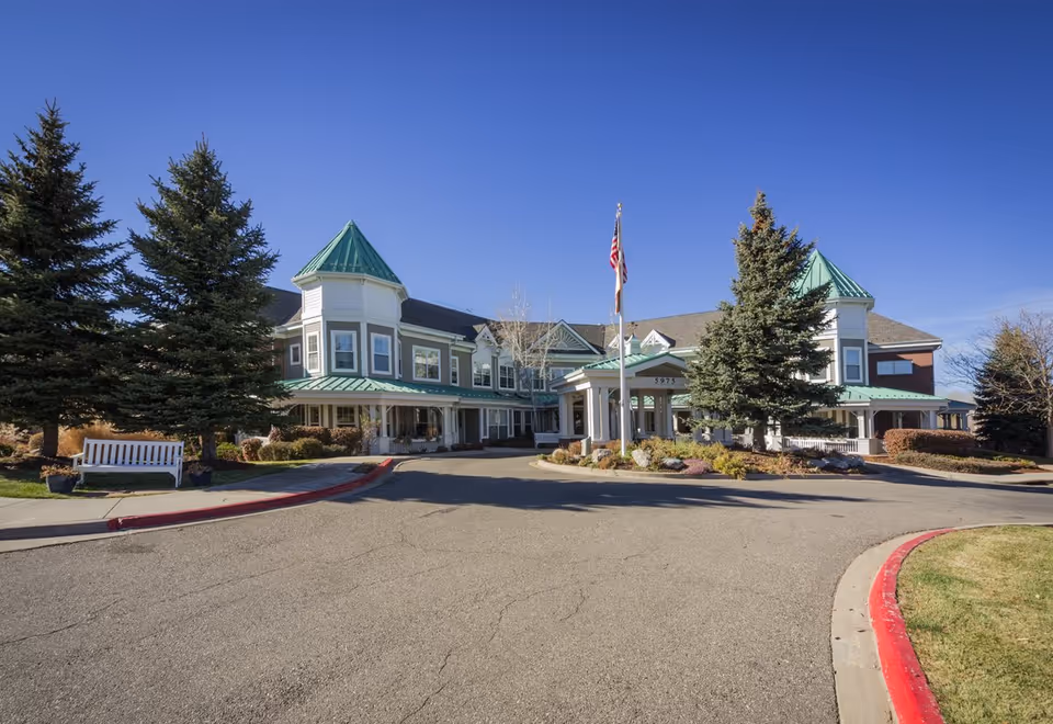 Front exterior of Sunrise at Orchard senior living facility with entrance and flag.