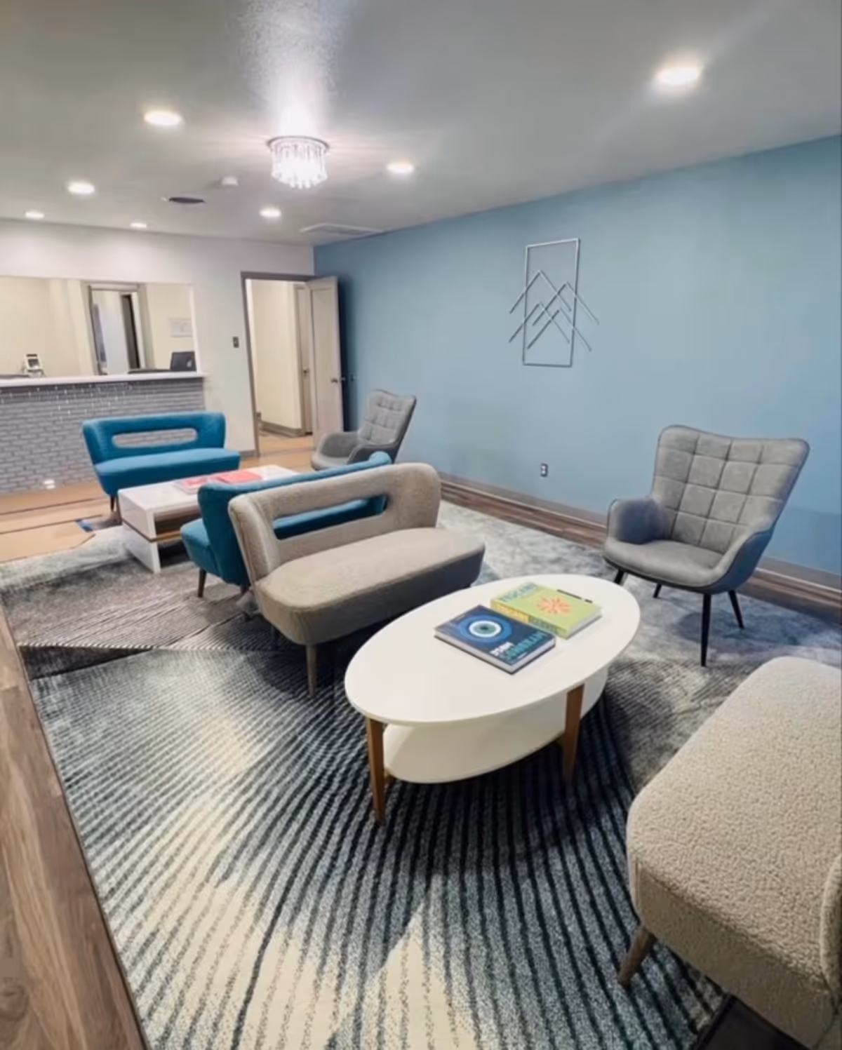 A modern lounge area with blue and gray seating, a coffee table, and a reception counter.