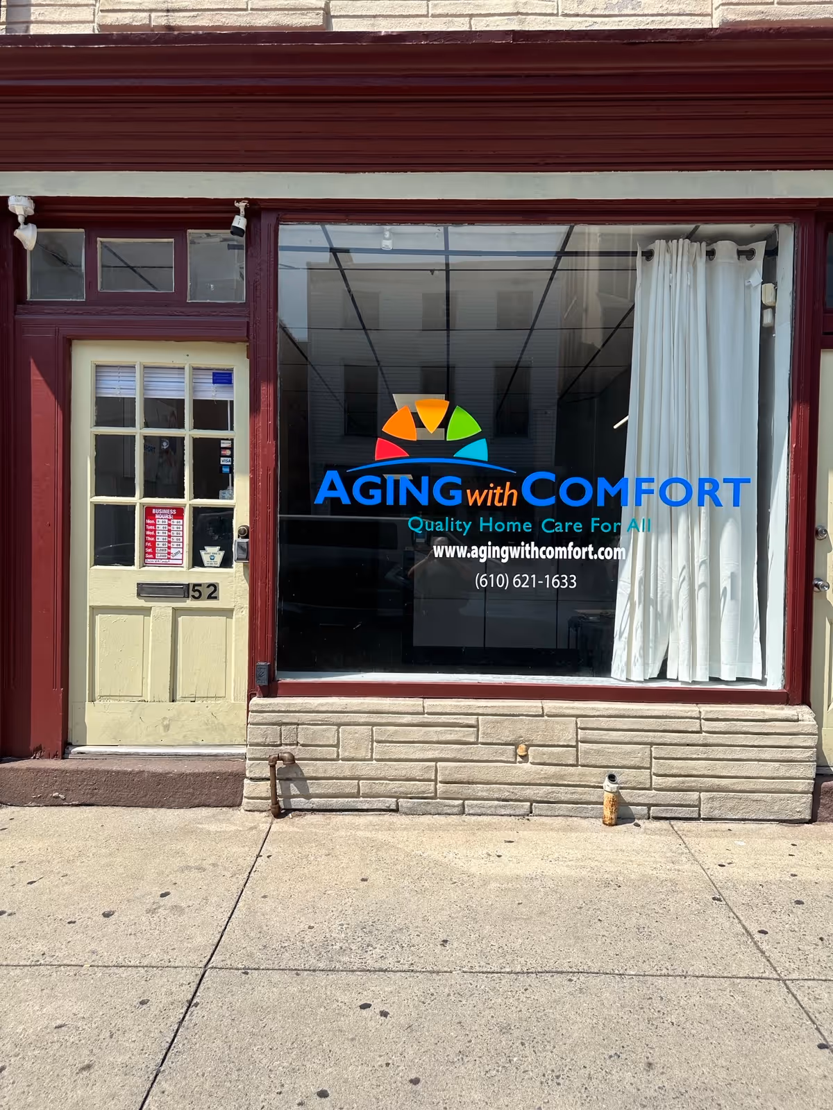 Exterior storefront for Aging with Comfort home care, featuring a large window sign and doorway.