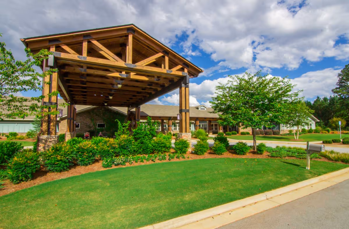Wooden covered entrance with landscaped garden leads to the Oaks at Braselton building.