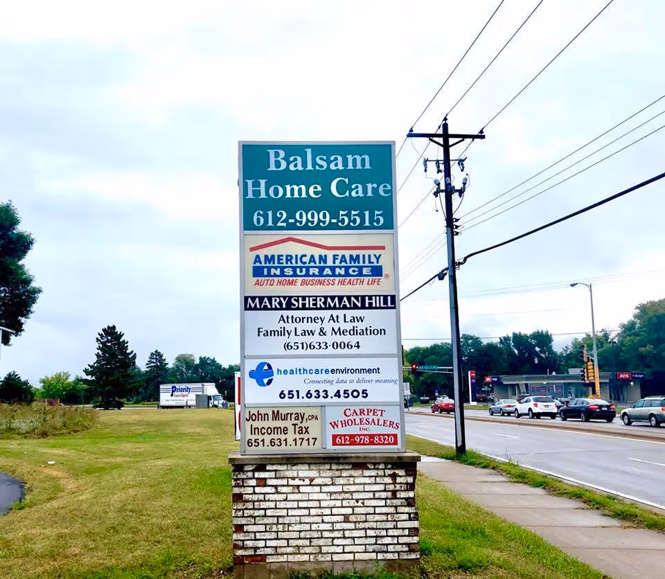 Tall roadside sign advertising Balsam Home Care and other services beside a busy road