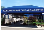 Blue canopy entrance with Fairlane Senior Care and Rehab Center sign, exterior walkway and landscaping.