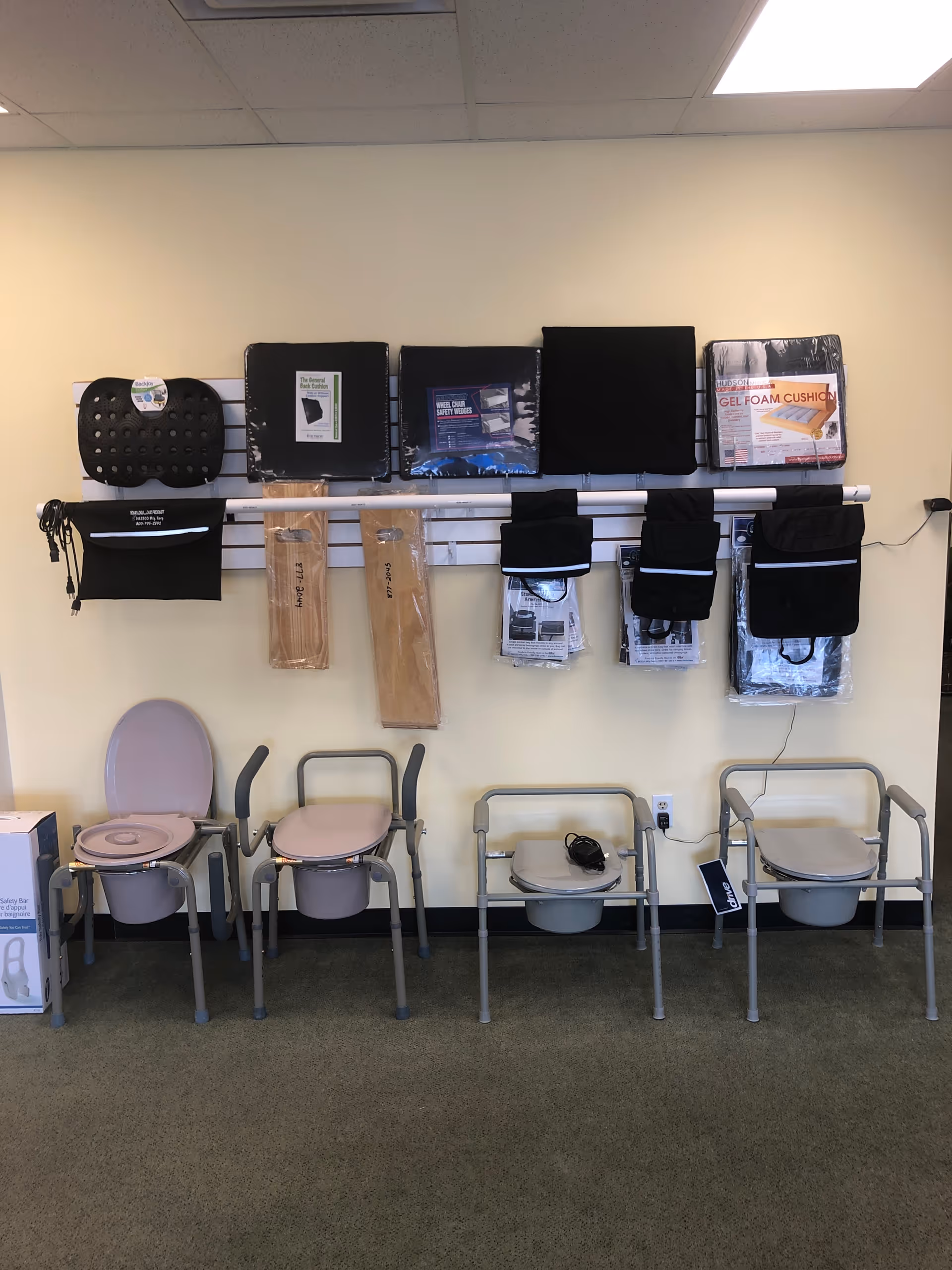 Interior showroom displaying wall-mounted mobility devices, cushions, and several seating chairs along the wall.