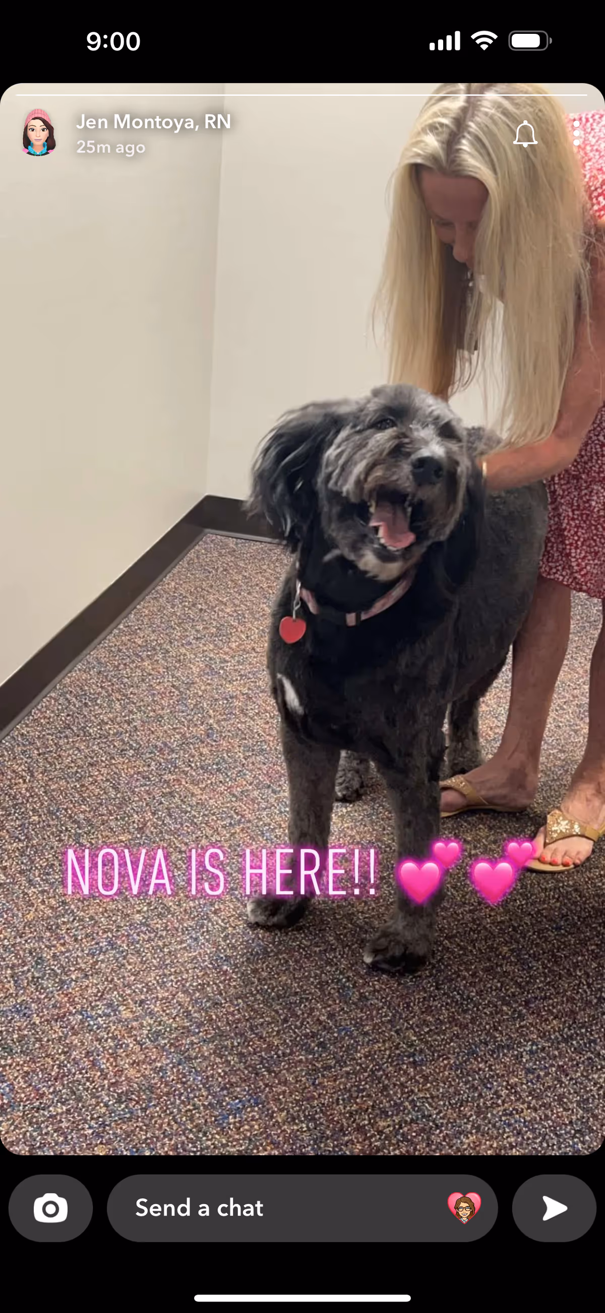A small dog with a woman in a hallway at a senior living facility.