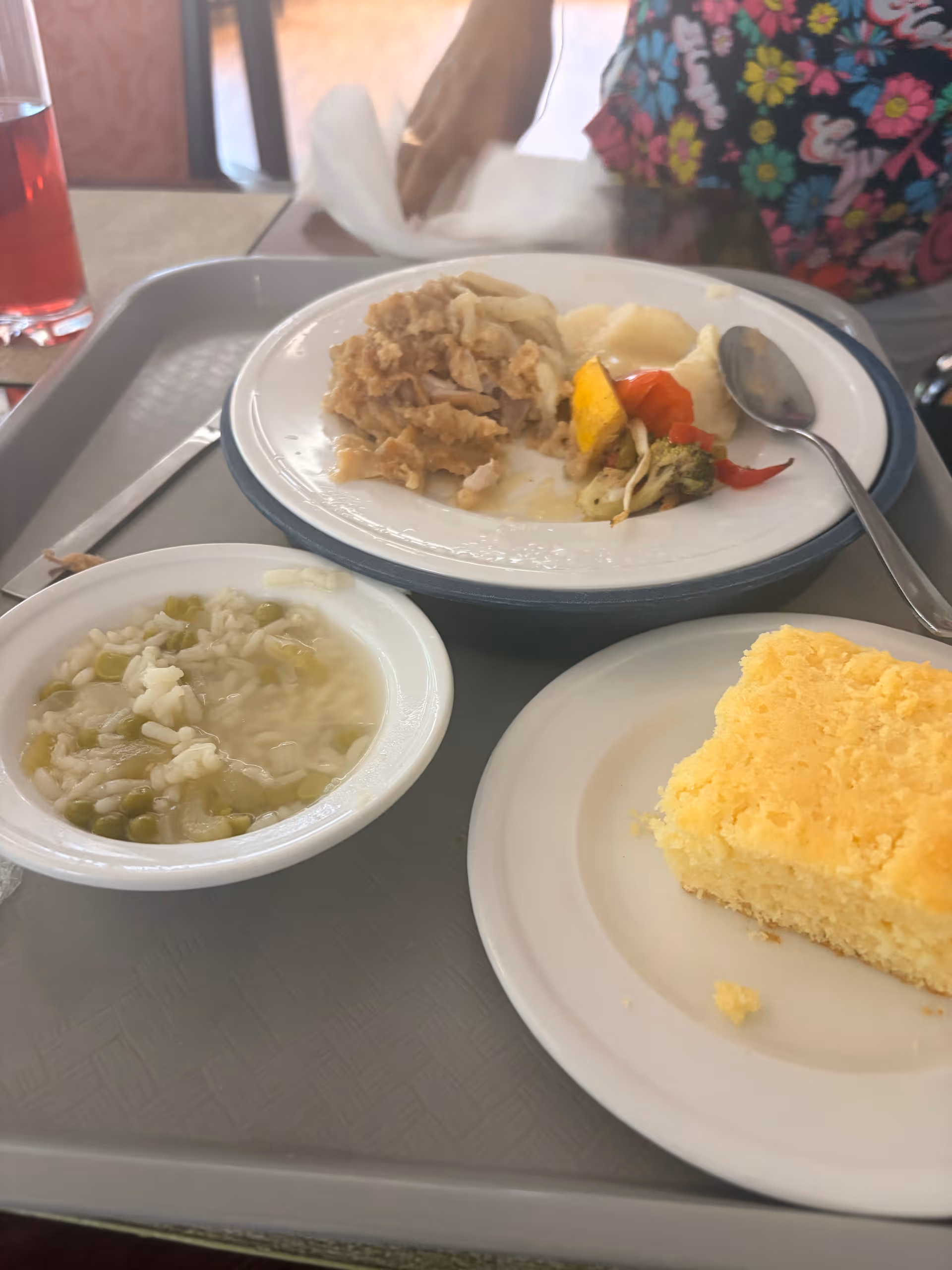 Dining tray with soup, casserole, vegetables, and yellow cake on a table.