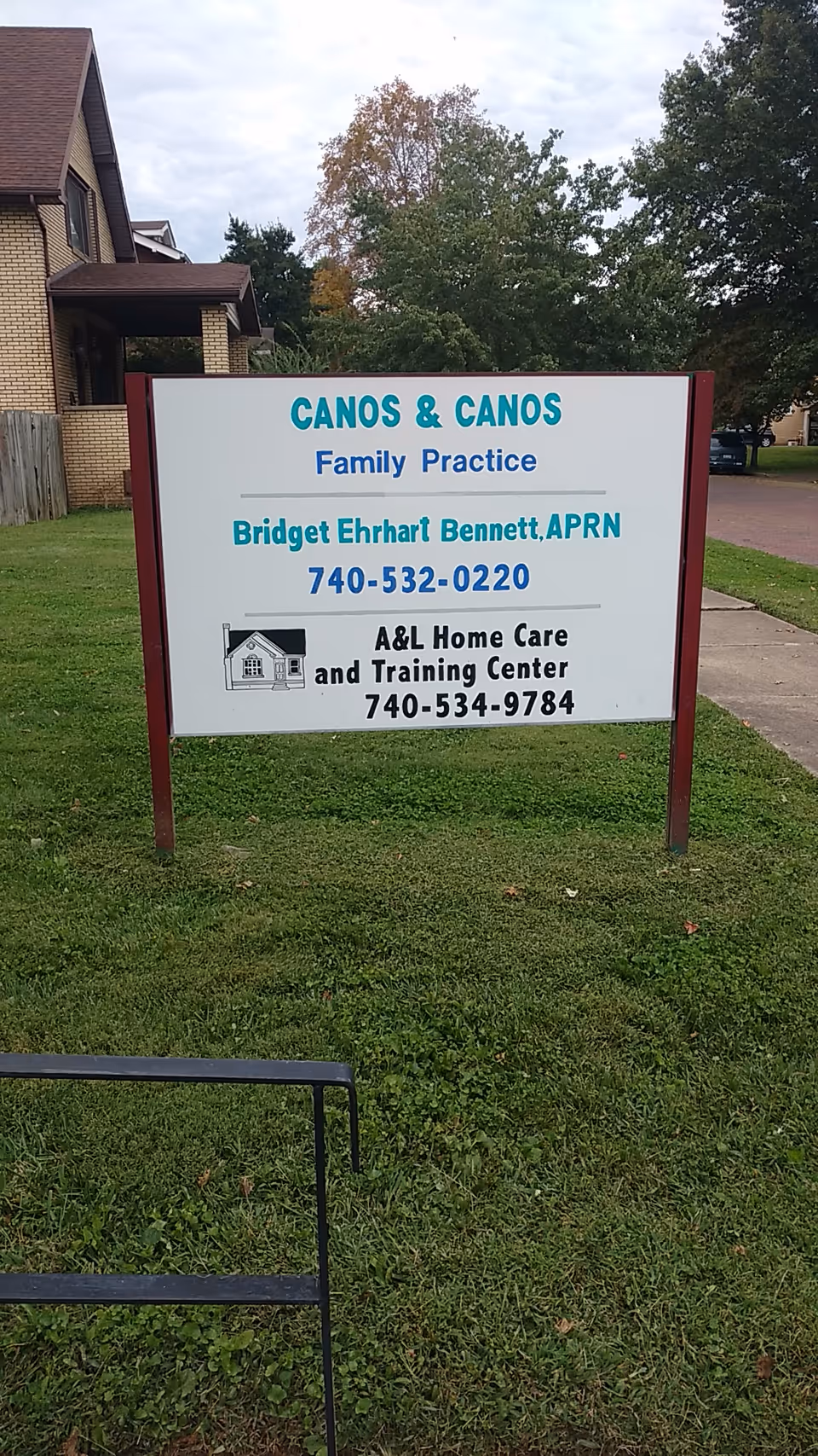 A large white sign on a grassy lawn advertising Canos & Canos and A&L Home Care.