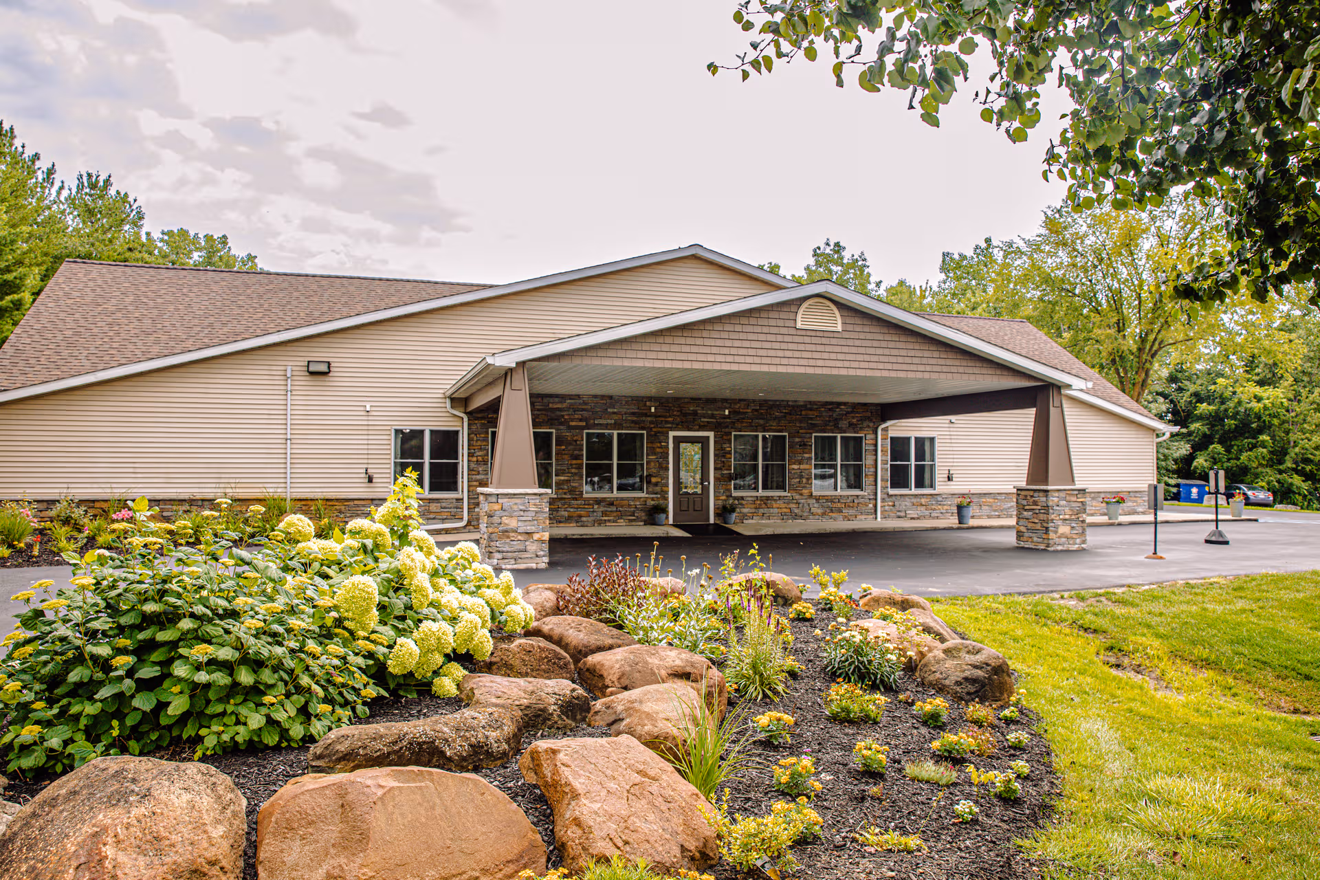 Front view of a single-story senior living facility with a covered entrance and landscaped garden.