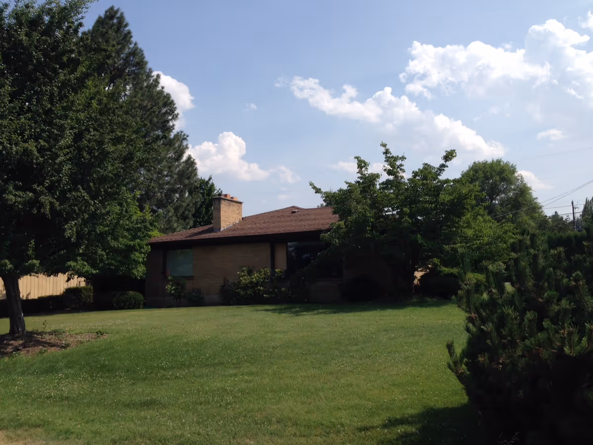 Front view of Henderson Adult Family Home with a green lawn and trees.