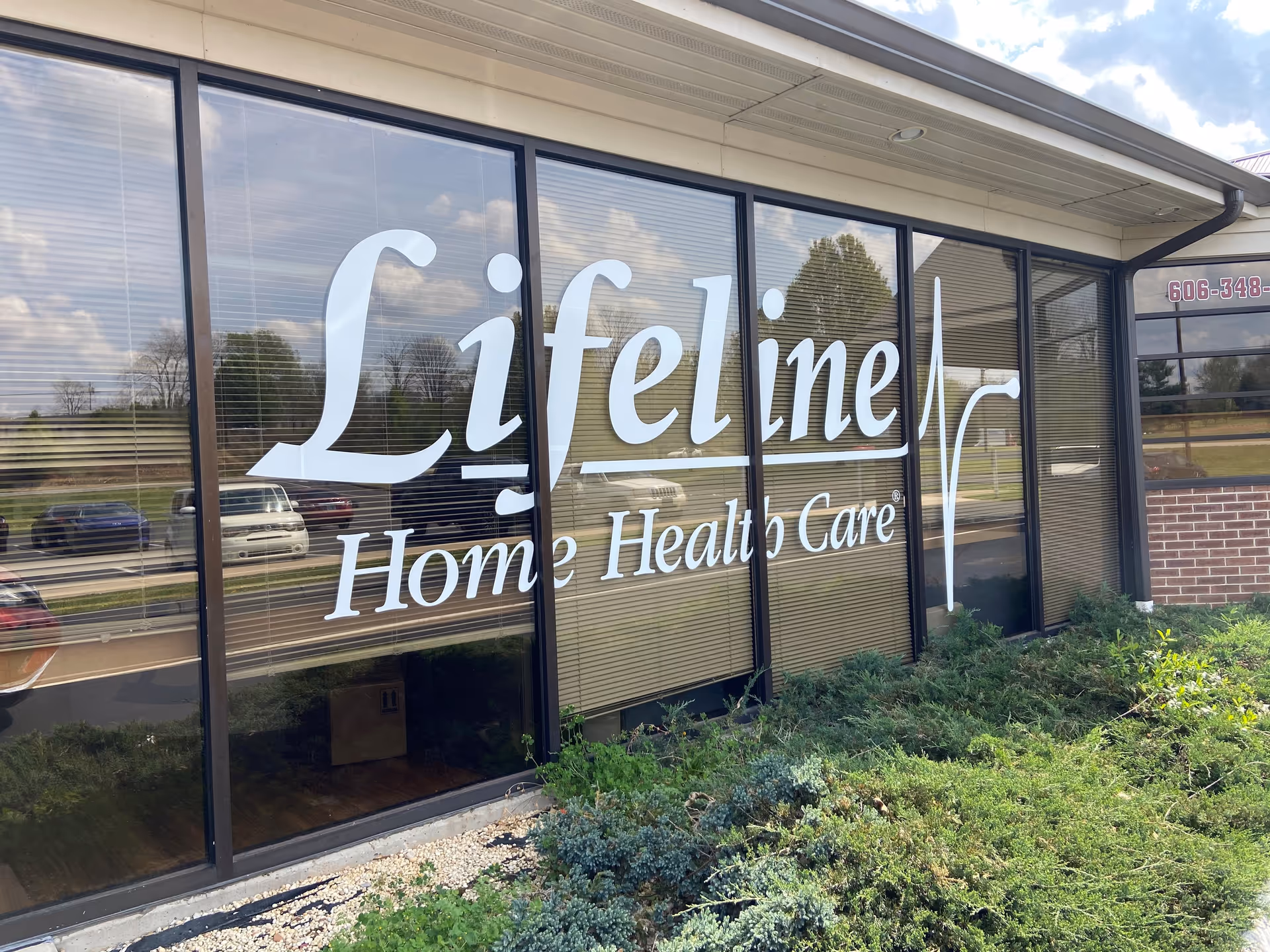 Exterior view of Lifeline Home Health Care facility with large glass signage and landscaping.