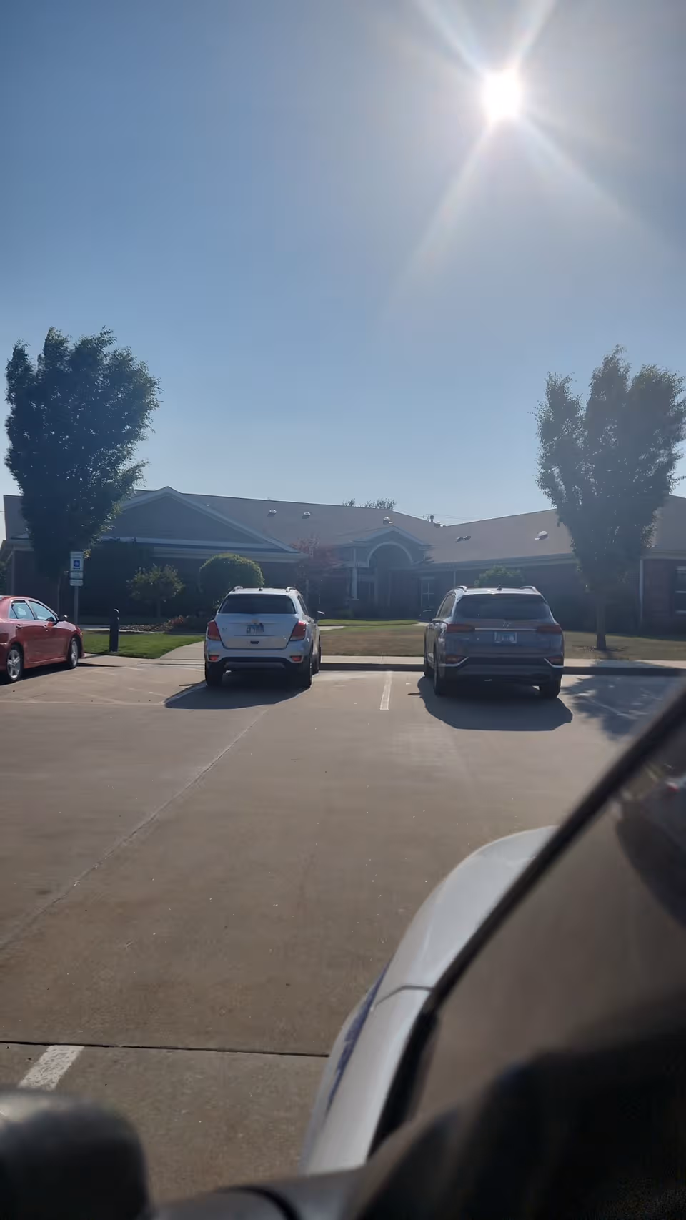 Sunny exterior view of Centennial Pointe Senior Living with a parking lot and entrance.