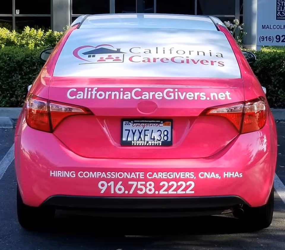 Rear view of a pink California CareGivers promotional car with logo and contact info.