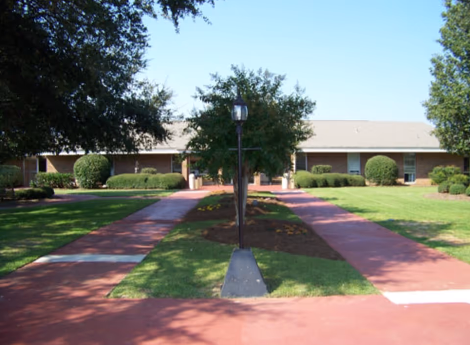 Exterior view of Warner Robins Rehabilitation Center with brick walkways and lush landscaping.