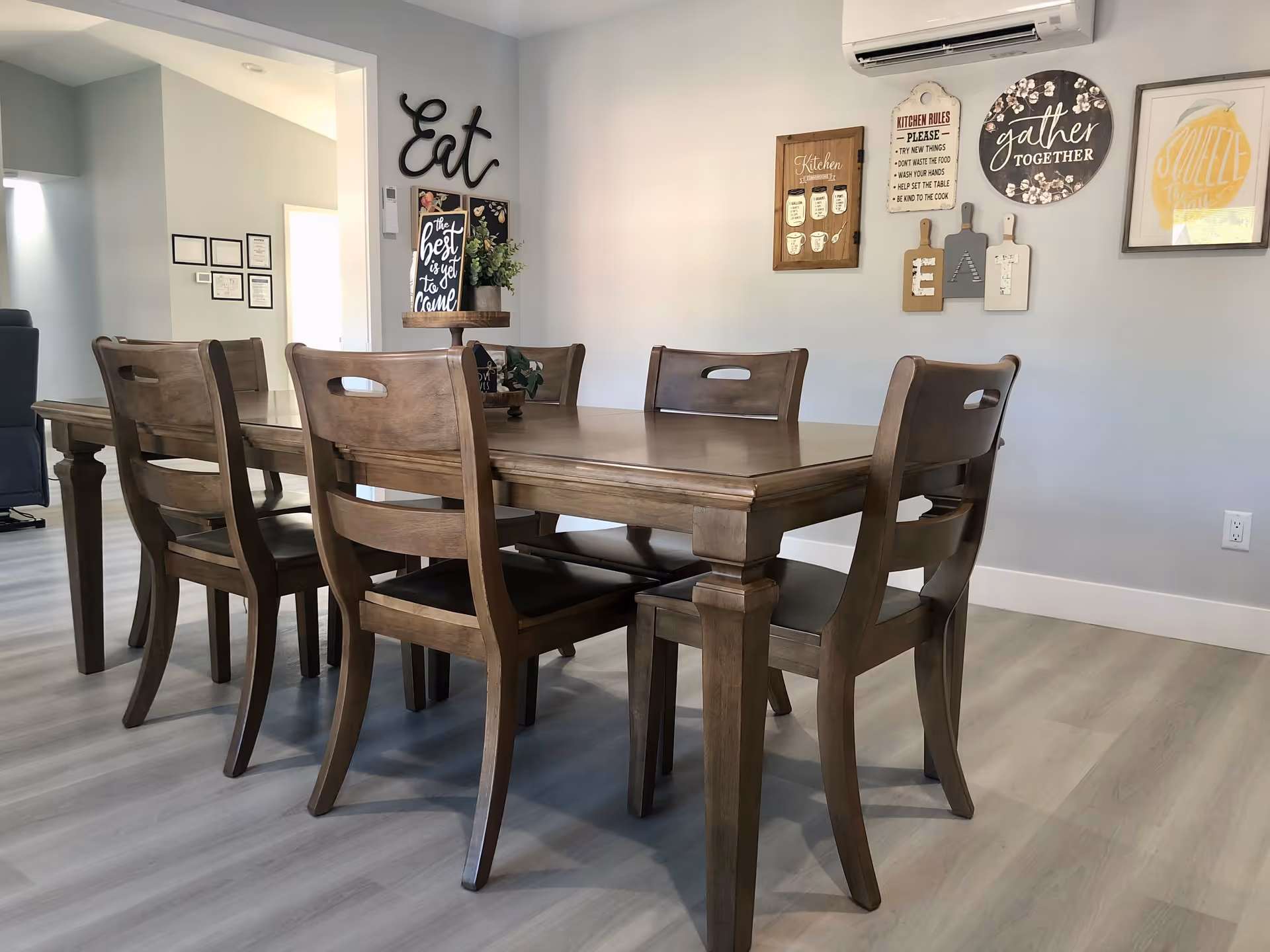 A wooden dining table with chairs in a bright care home dining area.
