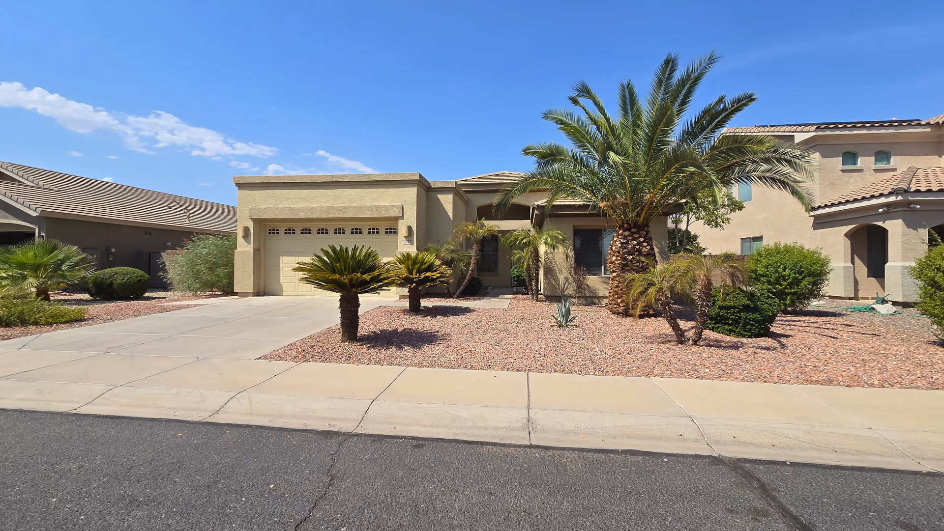 Single-story beige senior living facility with desert landscaping and a two-car garage.