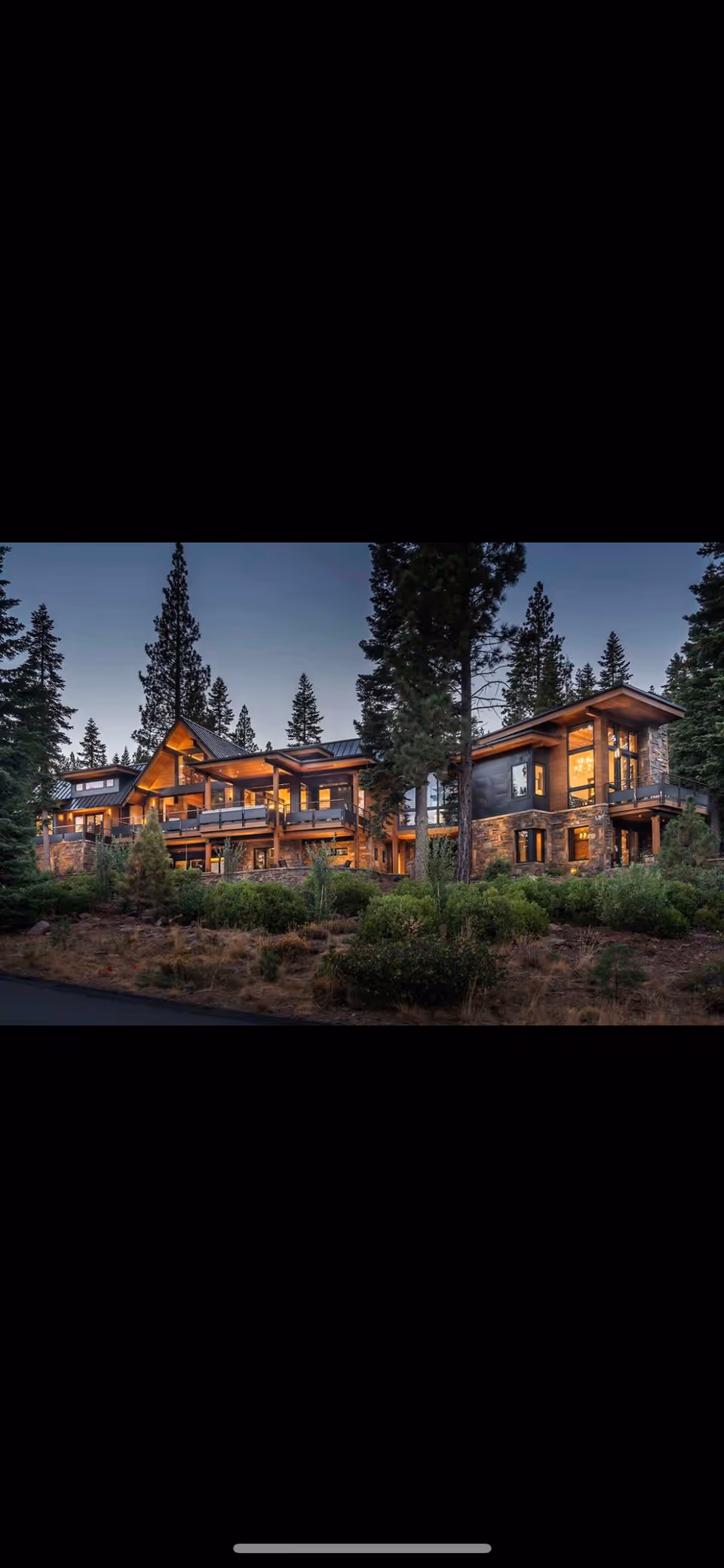 Wooden lodge-style senior living facility exterior surrounded by trees at dusk