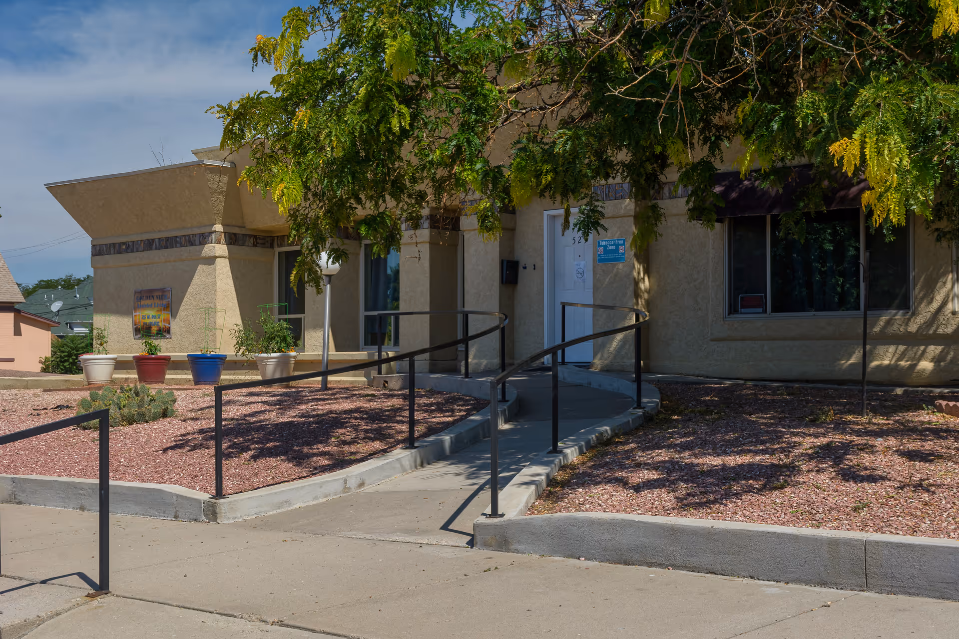 Exterior view of Health Solutions Grand House entrance with ramp and mulched landscaping.