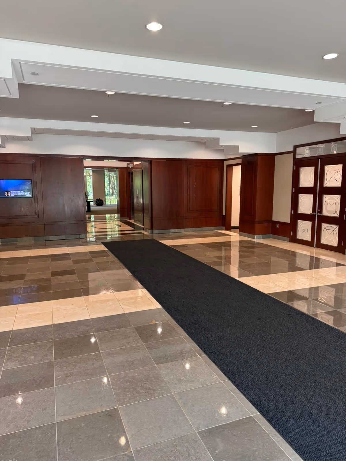 Lobby area of a senior care facility with tiled floor, dark wood walls, and carpet runner.