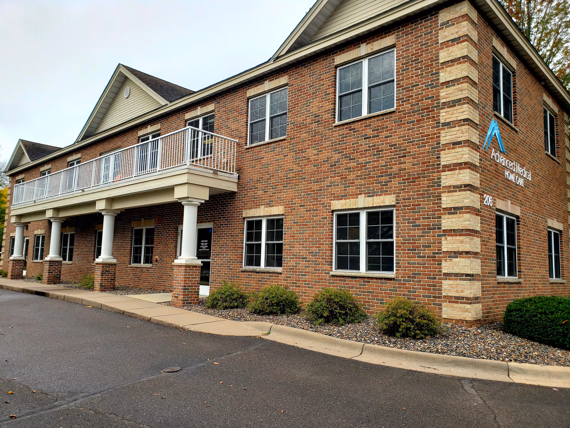 Brick two-story Advanced Medical Home Care facility with white-columned porch and balcony.