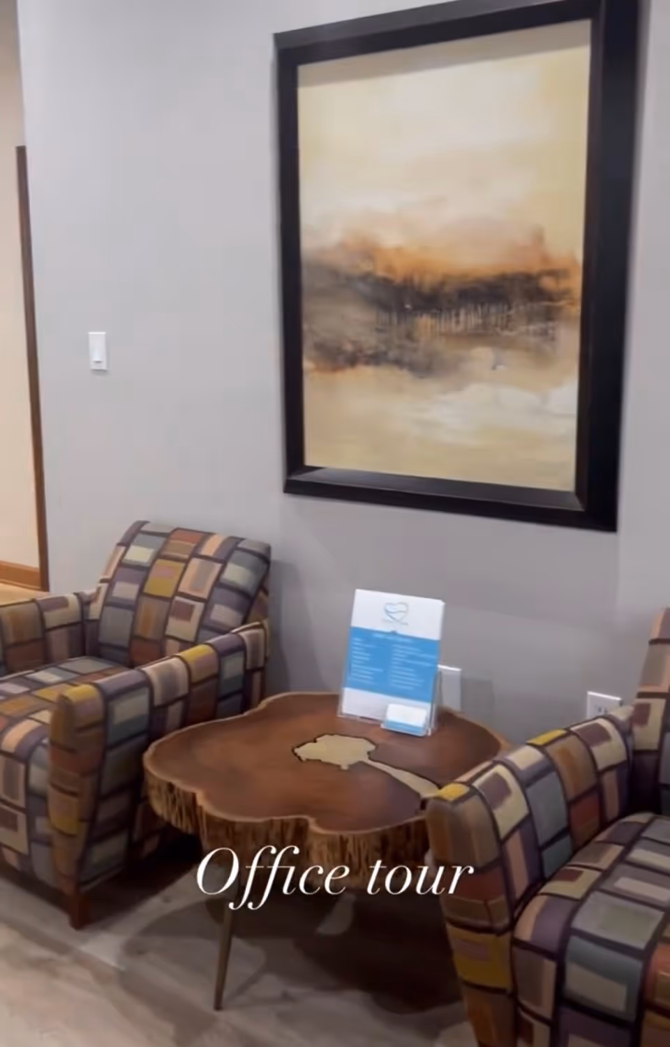 Two patterned armchairs flank a live-edge wood coffee table in a gray-walled lounge.