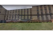 Multi-story beige senior living facility with grassy foreground and outdoor seating.
