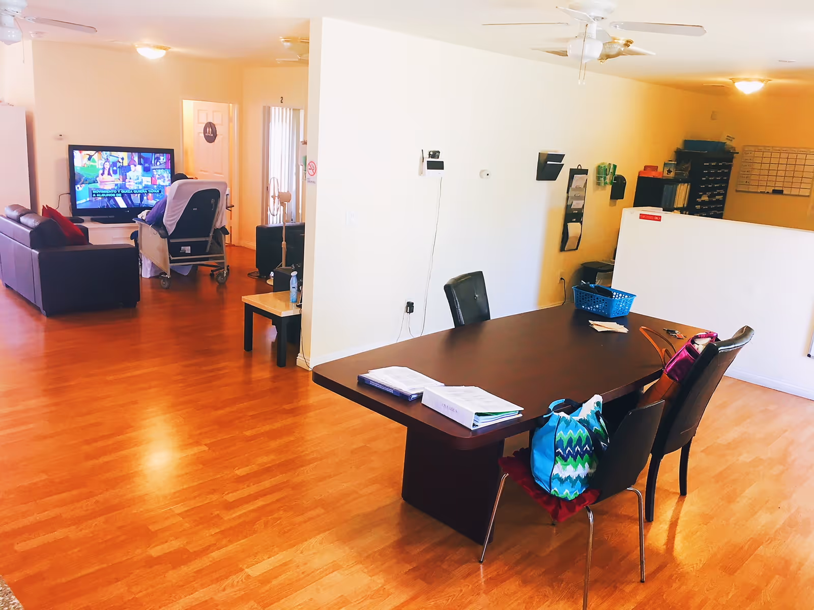 Open senior living common area with a dining table, chairs, and a TV seating area.