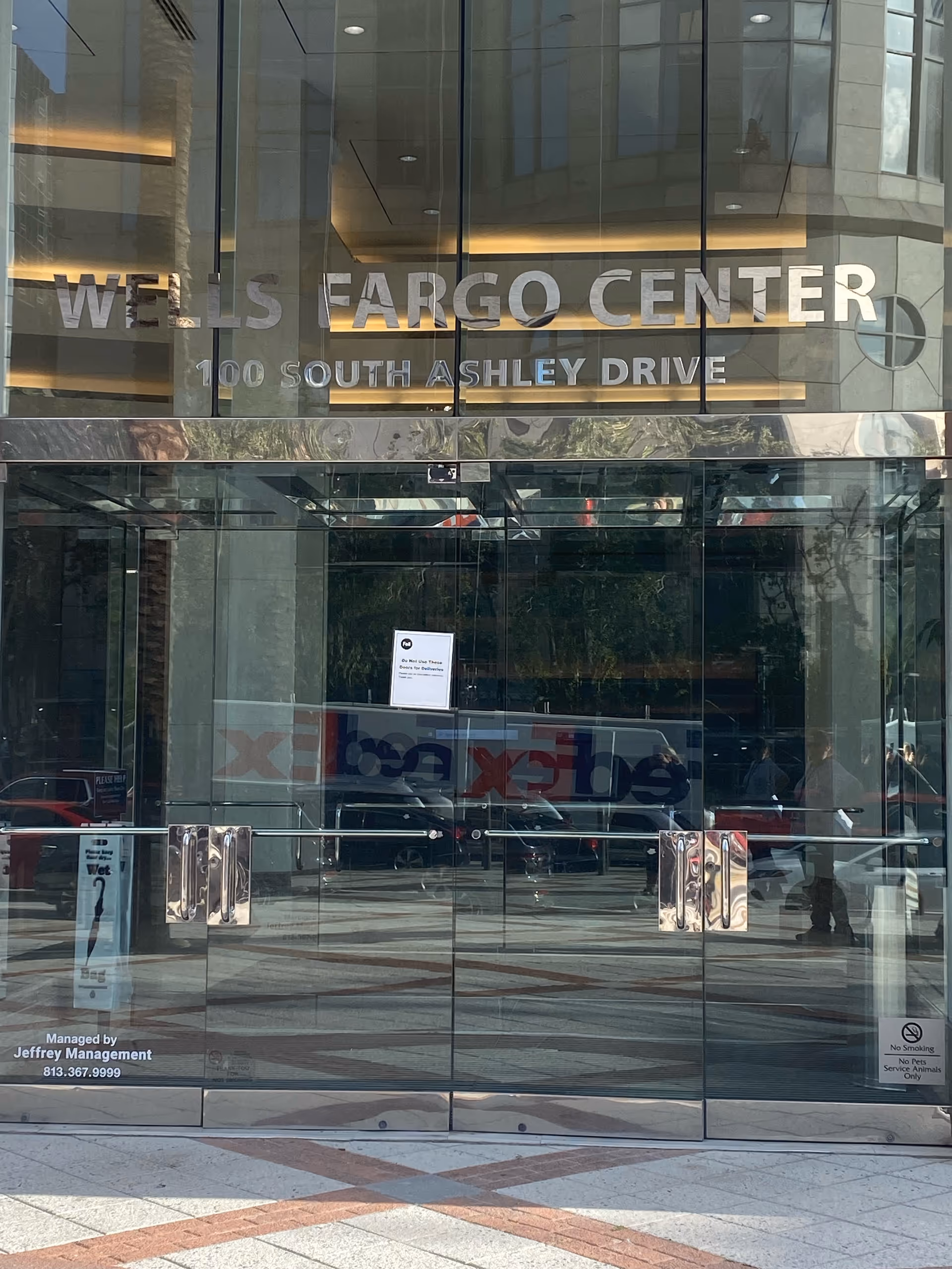 Glass-front entrance of Wells Fargo Center with large signage and reflective doors.