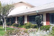 Front view of a single-story senior facility with shrubs and a lawn.