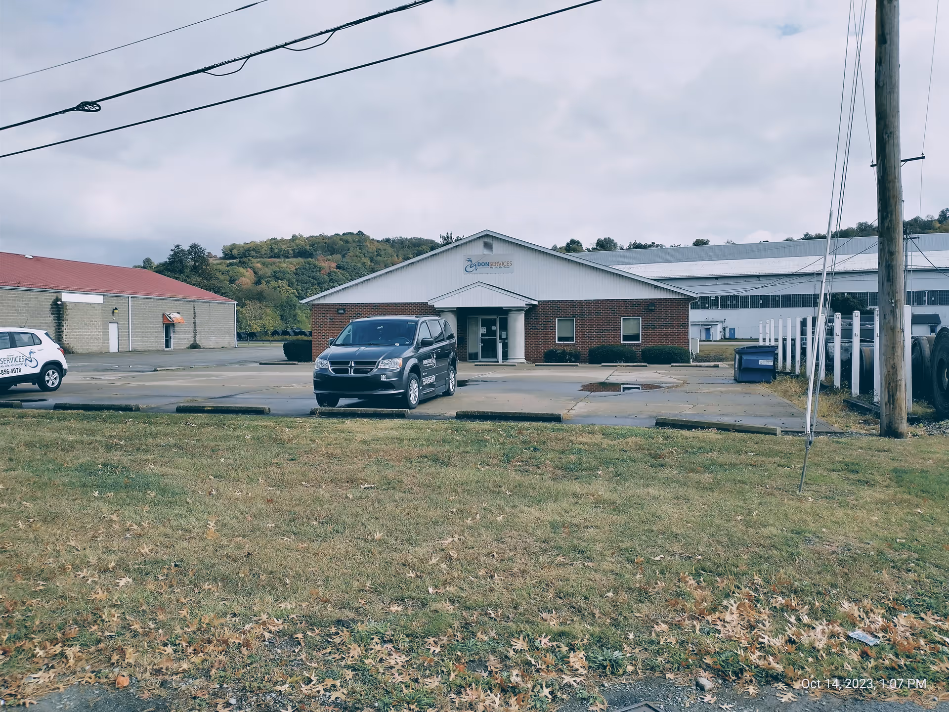 Exterior view of a DON Services building with a parking lot and cars.